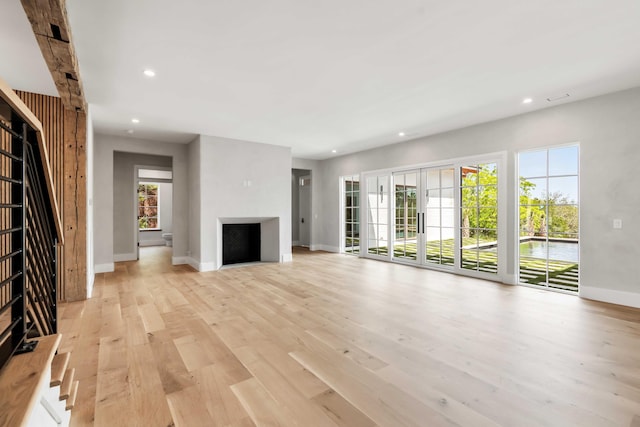 unfurnished living room featuring recessed lighting, baseboards, light wood finished floors, and a fireplace