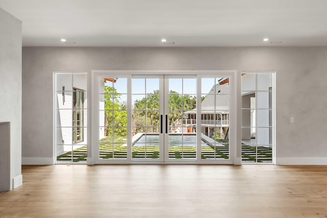doorway with wood finished floors, recessed lighting, baseboards, and french doors