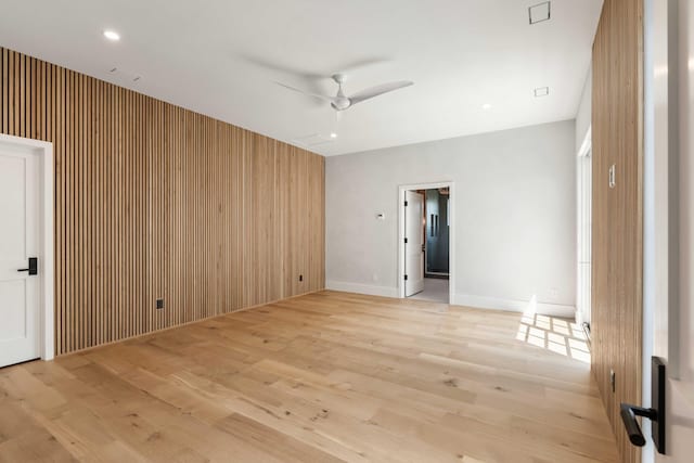 unfurnished room with a ceiling fan, light wood-style floors, and baseboards