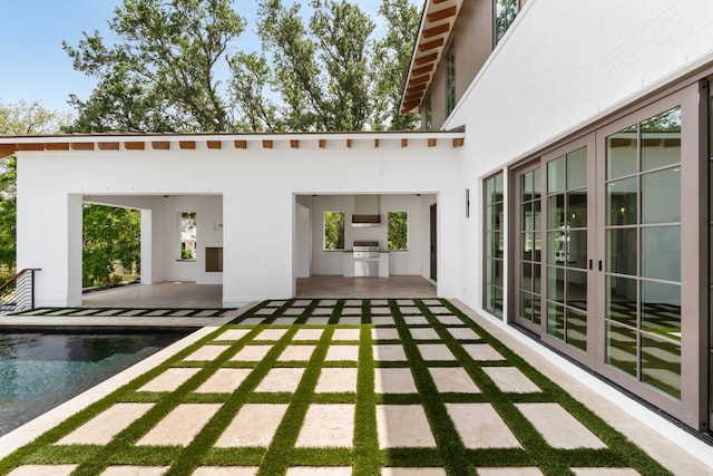 back of house with french doors, a patio, area for grilling, an outdoor pool, and stucco siding