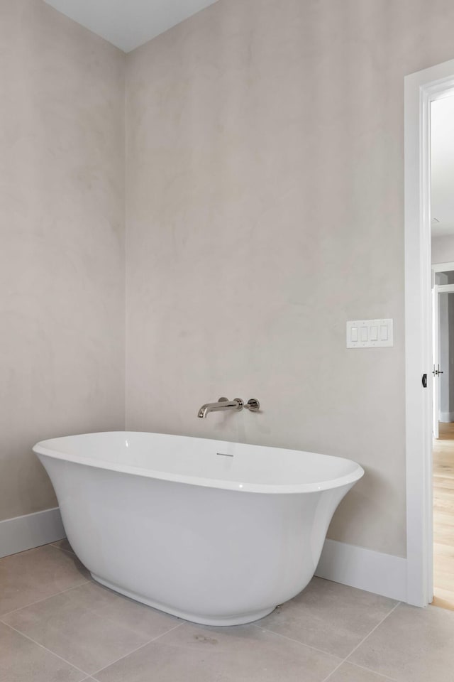 bathroom featuring baseboards, tile patterned flooring, and a soaking tub