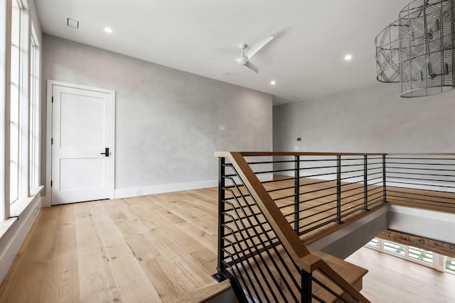 hallway featuring wood finished floors, an upstairs landing, and recessed lighting