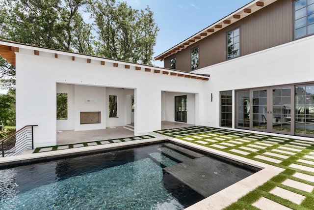 rear view of house with a patio, an outdoor pool, and stucco siding