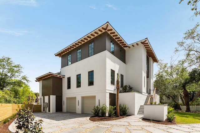 view of front of house featuring an attached garage, fence, and stucco siding