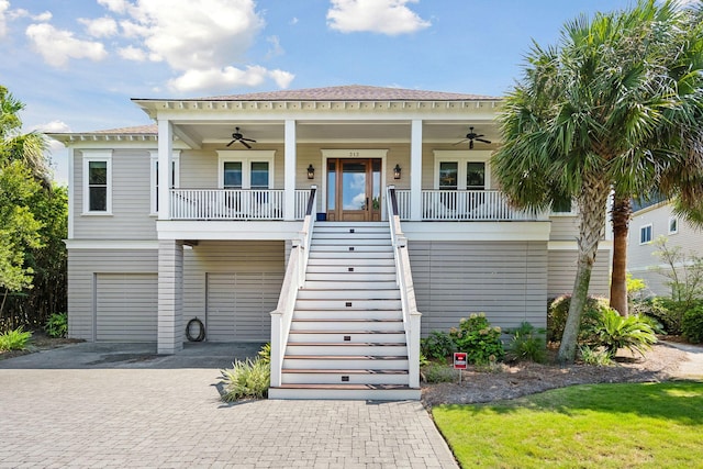 raised beach house with ceiling fan, a garage, and covered porch