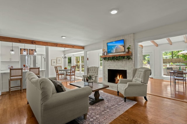 living room with beamed ceiling, a fireplace, and light wood-style floors