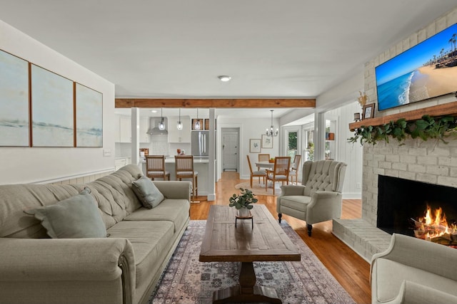 living area featuring a notable chandelier, light wood-style floors, and a fireplace