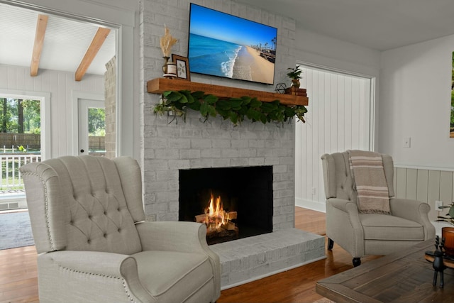 sitting room featuring beamed ceiling, wood finished floors, and a fireplace