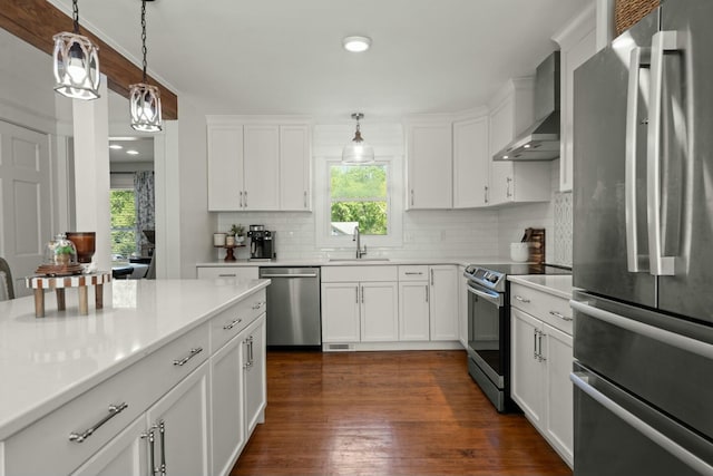 kitchen featuring tasteful backsplash, a sink, pendant lighting, stainless steel appliances, and wall chimney exhaust hood