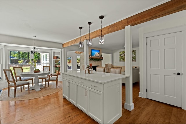 kitchen with light wood finished floors, a notable chandelier, light countertops, a fireplace, and hanging light fixtures