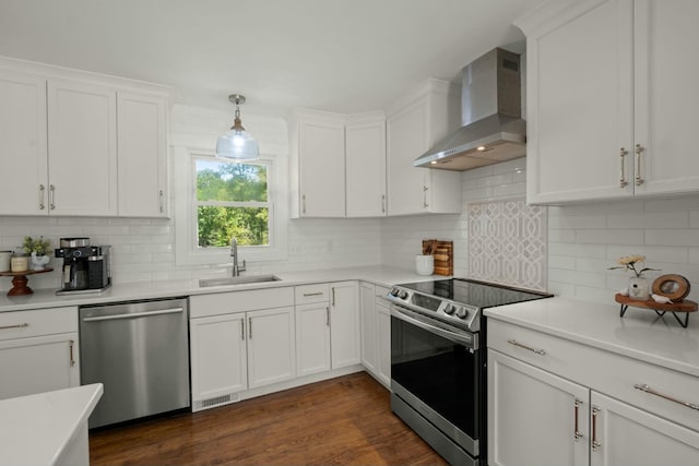 kitchen featuring wall chimney exhaust hood, a sink, white cabinetry, and appliances with stainless steel finishes