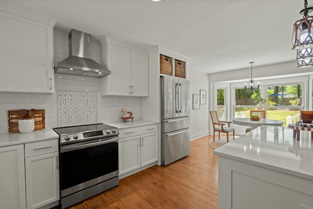 kitchen featuring wall chimney range hood, appliances with stainless steel finishes, and light countertops