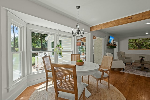 dining room featuring beamed ceiling, a chandelier, a wealth of natural light, and light wood-style floors