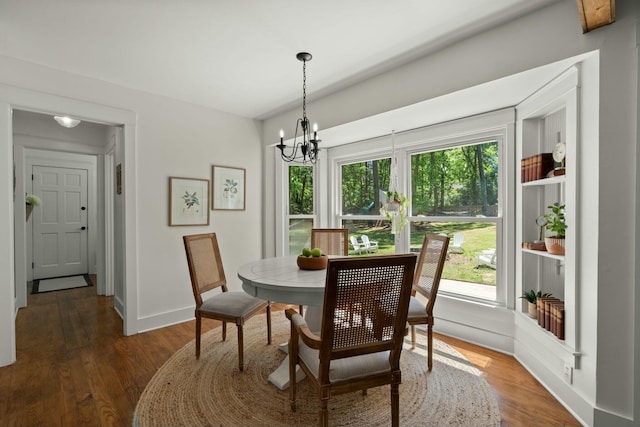 dining area featuring baseboards, a healthy amount of sunlight, wood finished floors, and a chandelier