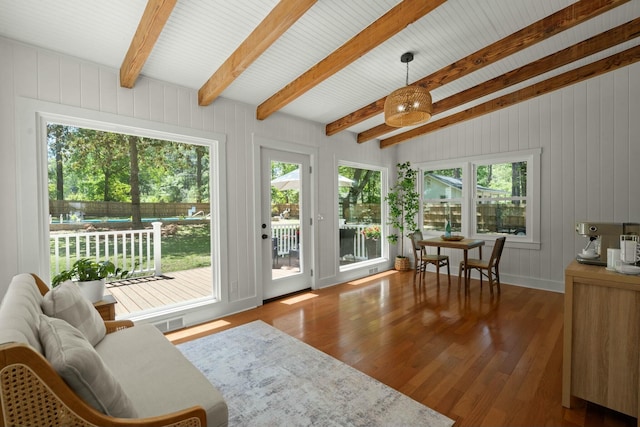 sunroom featuring beamed ceiling, a wooden deck, wood finished floors, and a wealth of natural light