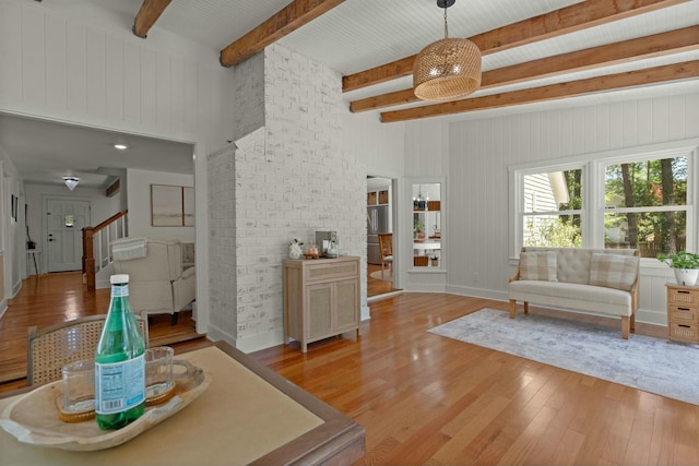 living room with a towering ceiling, beam ceiling, stairs, and light wood-style floors
