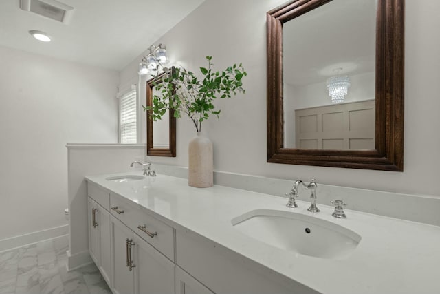 bathroom featuring baseboards, marble finish floor, a sink, and double vanity