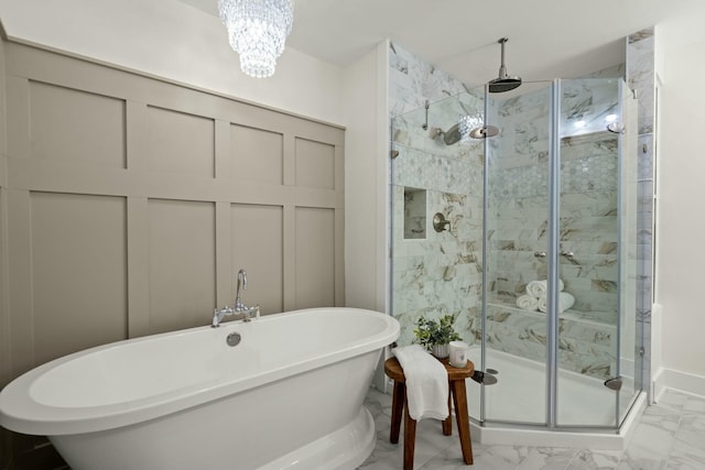 full bath featuring a freestanding tub, marble finish floor, a stall shower, and an inviting chandelier