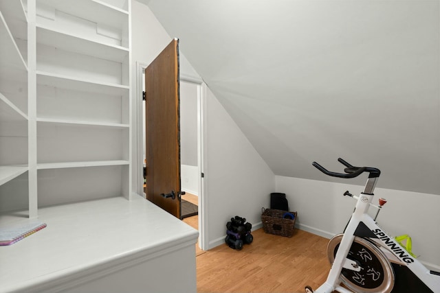 exercise room with vaulted ceiling and light wood-type flooring