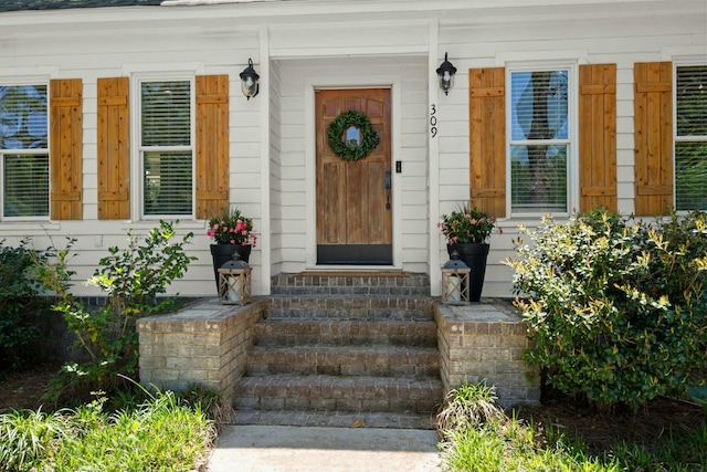 entrance to property featuring roof with shingles