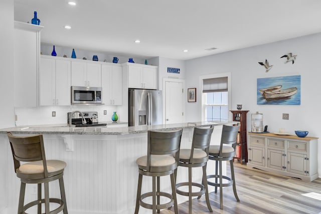 3473 Plow Ground Rd, Johns Island, SC 29455 - kitchen with stainless steel appliances, a peninsula, a breakfast bar area, recessed lighting, and light wood-style flooring