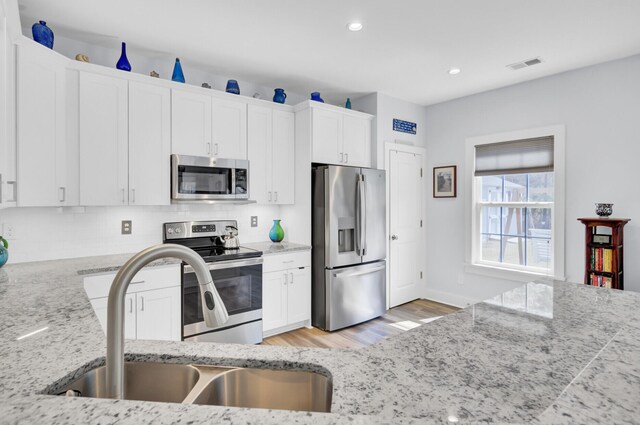 3473 Plow Ground Rd, Johns Island, SC 29455 - kitchen featuring appliances with stainless steel finishes, a sink, white cabinets, light wood finished floors, and recessed lighting