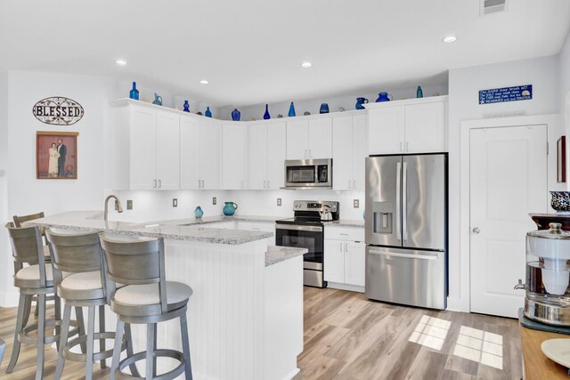 3473 Plow Ground Rd, Johns Island, SC 29455 - kitchen with appliances with stainless steel finishes, a kitchen bar, a peninsula, white cabinets, and recessed lighting