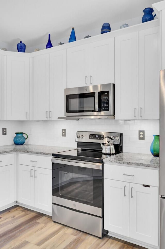 3473 Plow Ground Rd, Johns Island, SC 29455 - kitchen featuring appliances with stainless steel finishes, light wood finished floors, white cabinets, and decorative backsplash