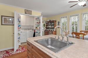 kitchen featuring independent washer and dryer, ceiling fan, a sink, light countertops, and brown cabinets