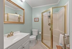 full bath featuring tile patterned floors, a stall shower, vanity, and ornamental molding