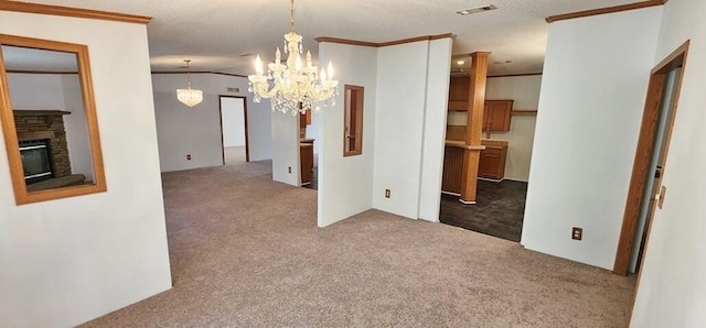 carpeted empty room featuring a textured ceiling, crown molding, a fireplace, and an inviting chandelier