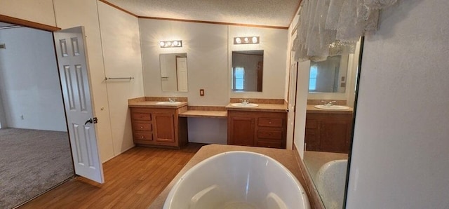 bathroom featuring a washtub, crown molding, wood-type flooring, a textured ceiling, and vanity