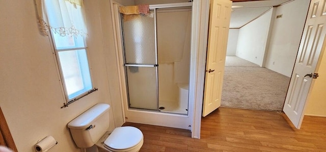 bathroom featuring toilet, a shower with door, and hardwood / wood-style flooring