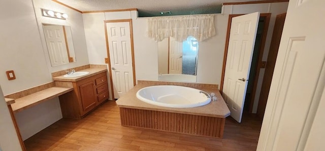 bathroom featuring hardwood / wood-style flooring, vanity, a tub to relax in, and a textured ceiling