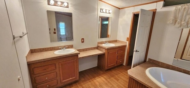 bathroom featuring vanity, crown molding, a tub to relax in, a textured ceiling, and wood-type flooring