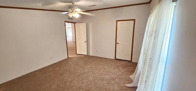 empty room featuring carpet flooring, a wealth of natural light, crown molding, and ceiling fan