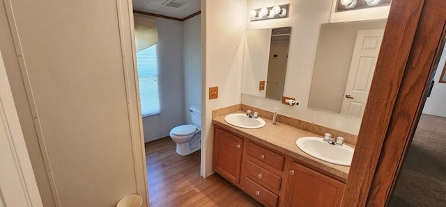 bathroom with hardwood / wood-style flooring, vanity, toilet, and crown molding