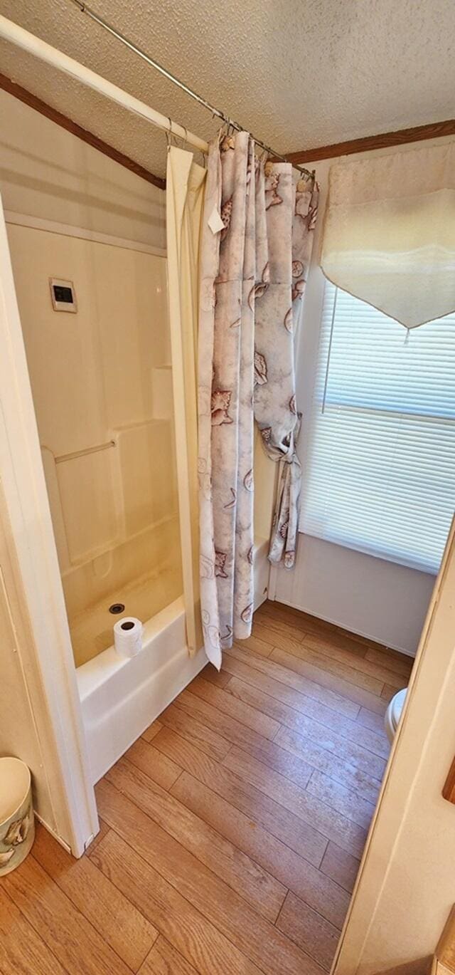 bathroom with shower / bath combination with curtain, a textured ceiling, hardwood / wood-style flooring, and vaulted ceiling