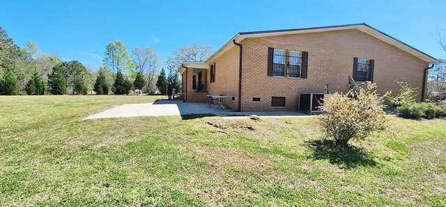 view of side of home featuring a yard, a patio, and central AC