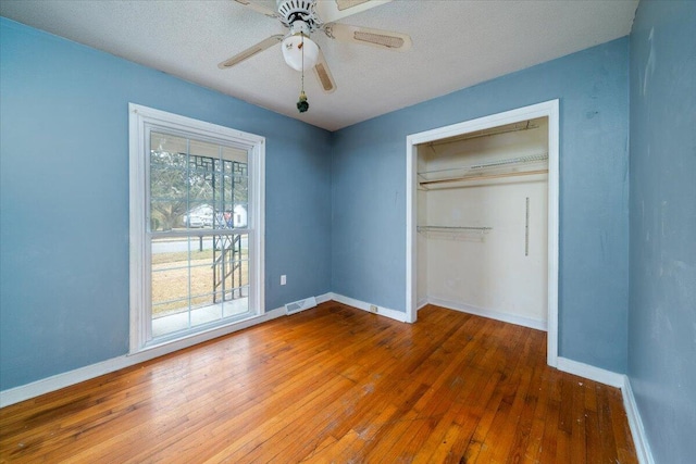 unfurnished bedroom featuring hardwood / wood-style flooring, ceiling fan, a closet, and a textured ceiling