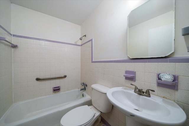 full bathroom featuring tile walls, sink, toilet, and tiled shower / bath