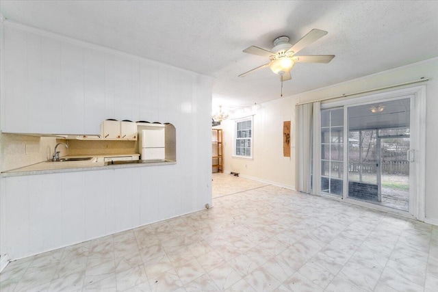 unfurnished living room featuring crown molding, ceiling fan, sink, and a textured ceiling