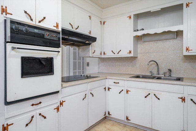 kitchen with tasteful backsplash, sink, white cabinets, oven, and black electric stovetop