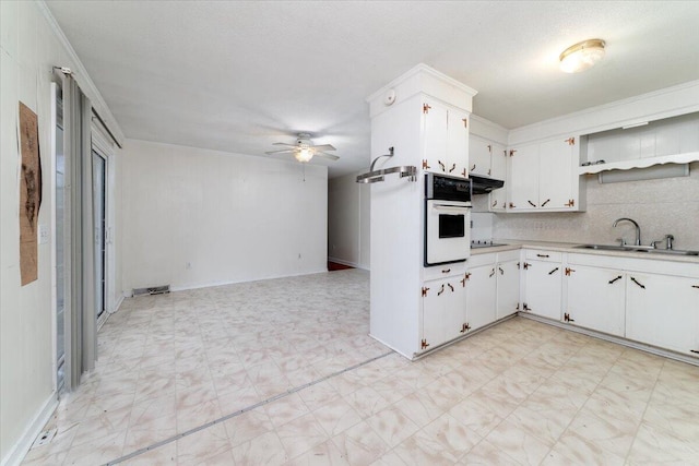 kitchen featuring sink, white oven, white cabinetry, backsplash, and black electric cooktop