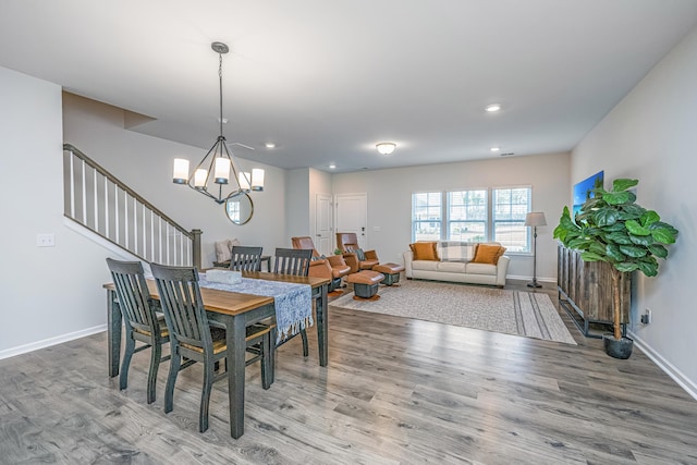 dining space with wood-type flooring and an inviting chandelier