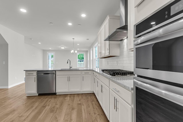 327 Hillman Trl Dr, Moncks Corner, SC 29461 - kitchen featuring appliances with stainless steel finishes, wall chimney exhaust hood, a sink, a peninsula, and white cabinetry