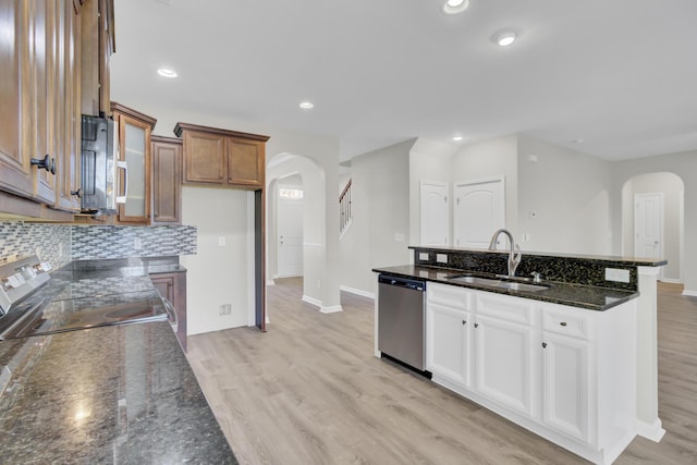 kitchen featuring dark stone counters, white cabinets, sink, light wood-type flooring, and appliances with stainless steel finishes