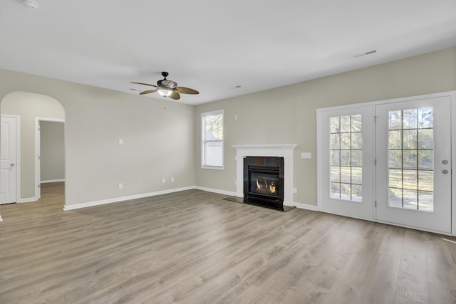 unfurnished living room featuring ceiling fan, light wood-type flooring, and a fireplace