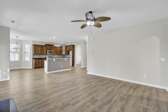 unfurnished living room featuring ceiling fan and light hardwood / wood-style flooring