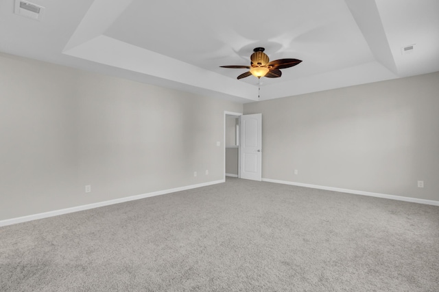 carpeted spare room with a tray ceiling and ceiling fan